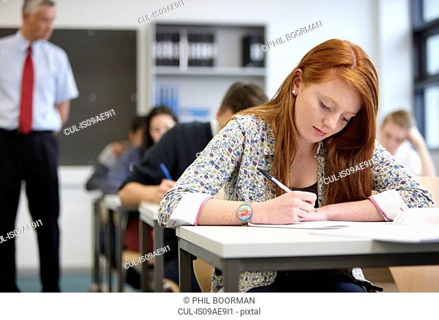 Teacher watching over teenagers in classroom