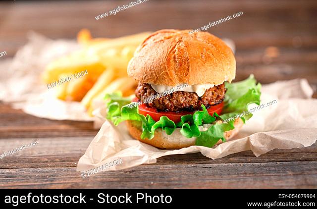 Homemade burger with french fries on wooden table