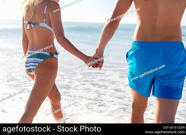 Caucasian couple standing in water at the beach