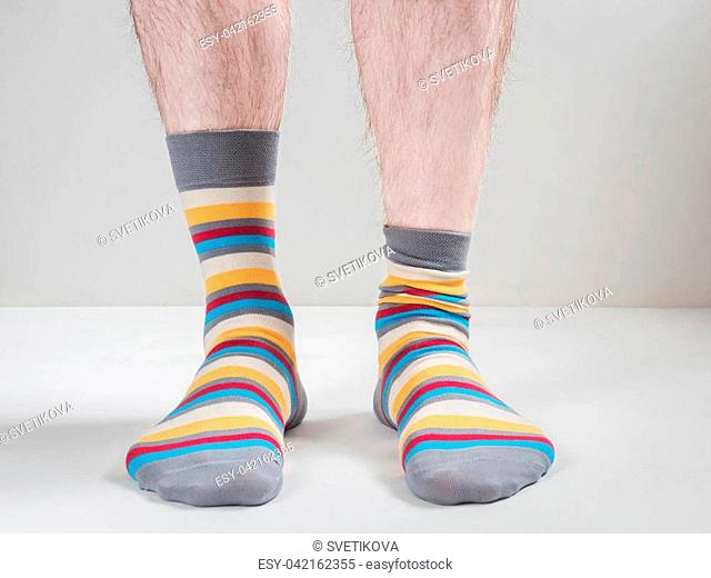 Men's feet in funny, colorful socks on a white background