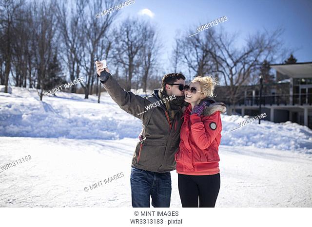 Caucasian couple taking cell phone selfie in winter