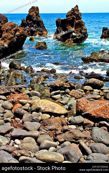 brown rock in white coast lanzarote  spain  beach stone water and summer hervideros