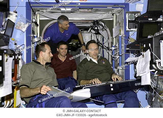 Astronaut Carl E. Walz (right), Expedition Four flight engineer, plays host to some crewmates as he performs on a musical keyboard in the Destiny laboratory on...