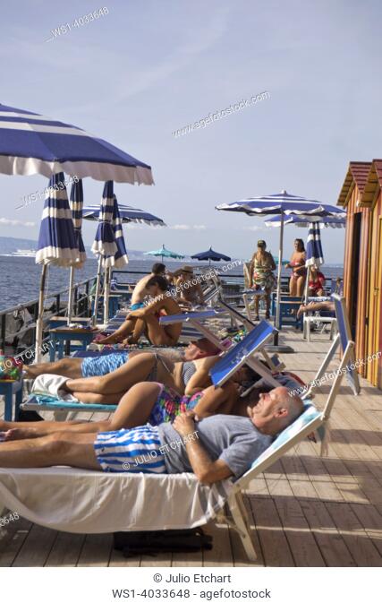 Tourists swimming and sunbathing at a private lido beach resort in the seaside resort of Sorrento near Naples, Italy