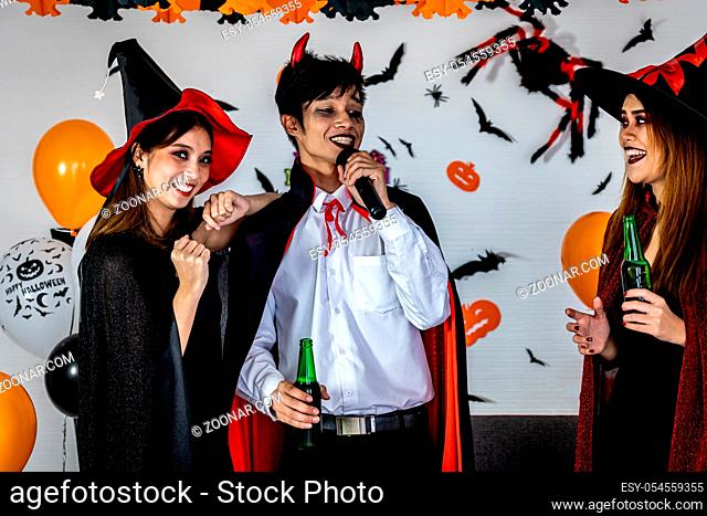 Group of young adult and teenager people celebrating a Halloween party carnival Festival in Halloween costumes drinking alcohol beer singing a song and dancing