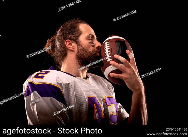 Close up portrait of American Football Player who gently kiss the ball