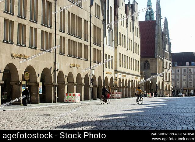 23 March 2020, North Rhine-Westphalia, Münster: Cyclists ride over the Prinzipalmarkt. In order to slow down the spread of the coronavirus