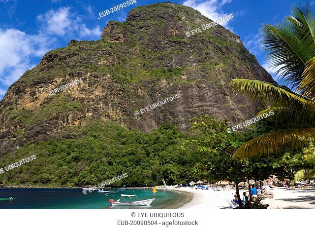 Val des Pitons The white sand beach at the Jalousie Plantation Resort Hotel with the volcanic plug of Petit Piton beyond and tourists on sunbeds beneath palapa...