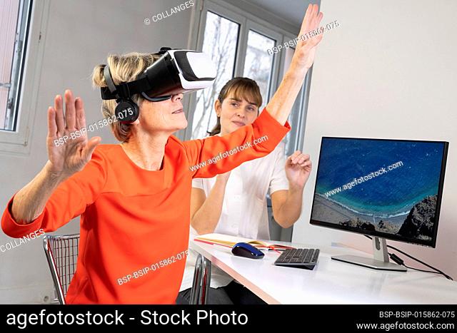 Elderly woman, during a therapy session with a virtual reality headset under the supervision of a therapist