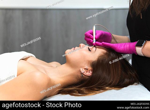 Young woman lying down during skin treatment at aesthetic center