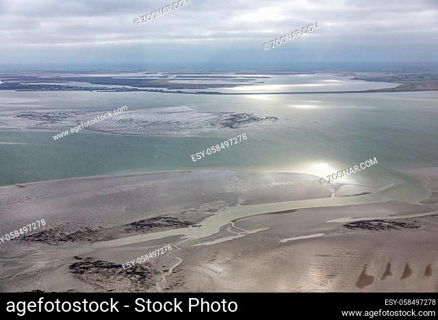 Aerial view at Dutch Wadden Sea with low tide, the sun is reflecting at the water