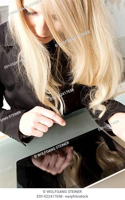 Langhaarige blonde Geschäftsfrau arbeitet mit Tablet PC