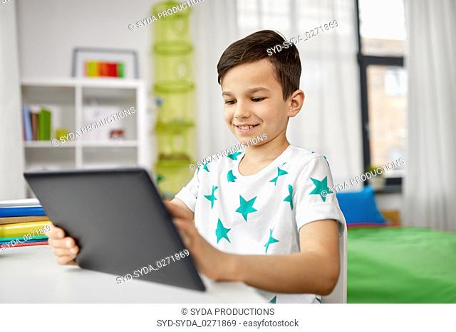 student boy with tablet pc and notebook at home