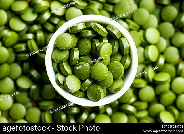 Green chlorella pills or green barley pills in bowl. Top view