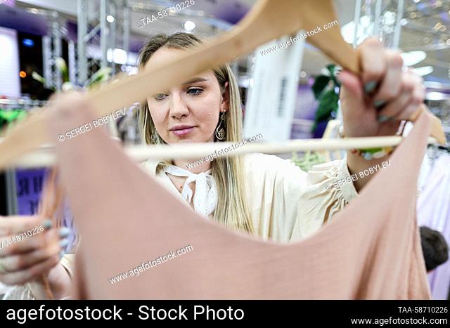 RUSSIA, MOSCOW - APRIL 28, 2023: A woman looks at a piece of clothing during the Moscow Fashion Week at the Oceania Shopping Centre