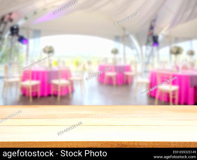 Light wooden empty table in front of blurred restaurant interior background. Perspective light wood board over blur in restaurant or cafe - mockup for display...
