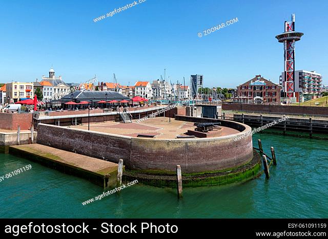 Vlissingen, The Netherlands - June 28, 2019: Mole in historic harbor Dutch Vlissingen with medieval canon and restaurant with terrace