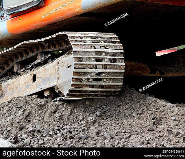 heavy orange crawler excavator is standing on the construction site of repair and expansion of the road