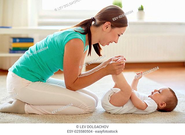 family, child and parenthood concept - happy smiling young mother playing with little baby at home