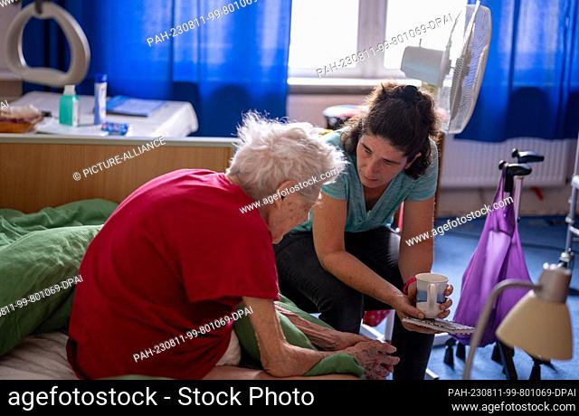 PRODUCTION - 31 July 2023, Berlin: Caregiver Ramona Rössner listens to her patient, 97-year-old senior Brigitte Richter, who is in need of care
