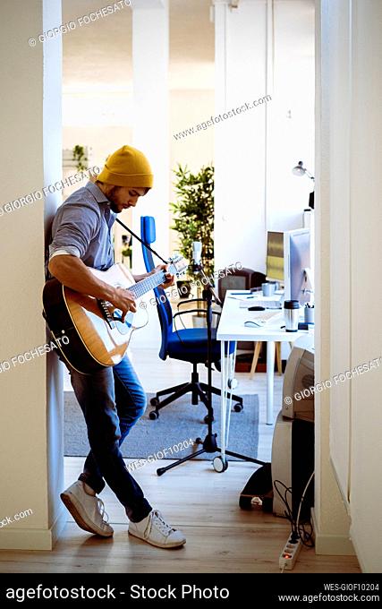 Guitarist playing guitar while standing at studio