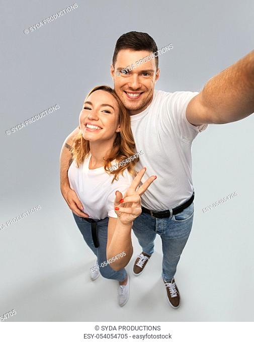 happy couple in white t-shirts taking selfie