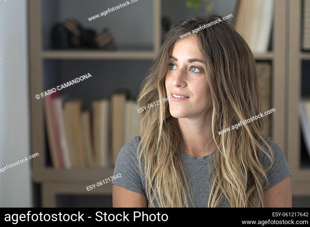 Beautiful healthy millennial single woman looking at camera at home. Happy young adult girl with attractive face standing in apartment