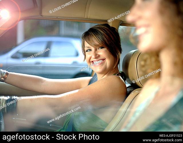 Cheerful woman with female friend driving car