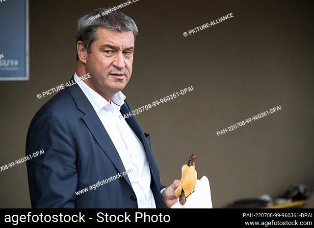 08 July 2022, Bavaria, Theres: Markus Söder (CSU), Minister President of the Free State of Bavaria, eats a bratwurst roll during the district party conference...