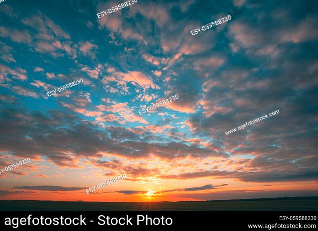 Sunset Sunrise Over Field Or Meadow. Bright Dramatic Sky And Dark Ground. Countryside Landscape Under Scenic Colorful Sky At Sunset Dawn Sunrise