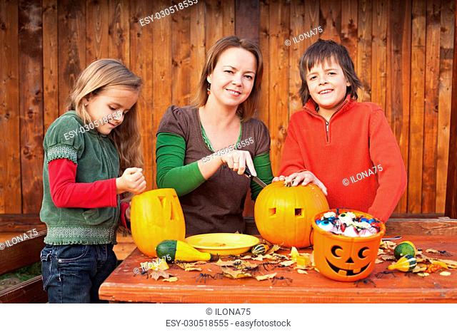 Family carving pumpkin lanterns for halloween - preparing the spooky accessories