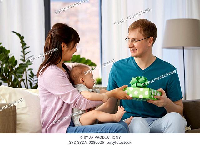 mother with baby giving birthday present to father