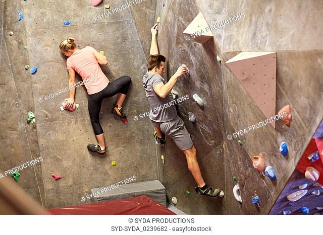man and woman training at indoor climbing gym wall