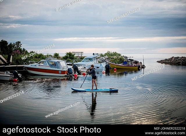 Woman paddleboarding, boats inn background