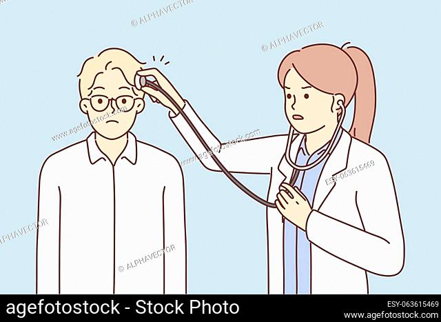 Woman doctor puts stethoscope on patient head for concept of treating headaches or neuro medicine. Girl doctor and man who turned to neurotherapist because of...