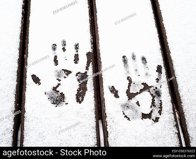 Imprints of hands in snow on a table outdoor