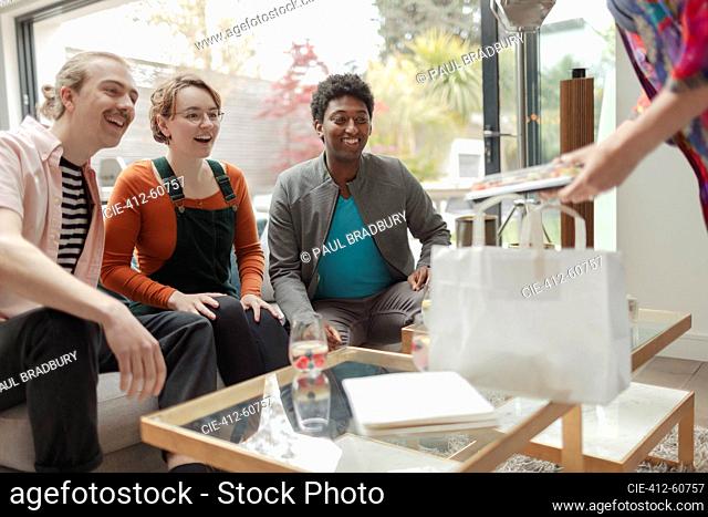 Woman serving takeout sushi to friends in living room