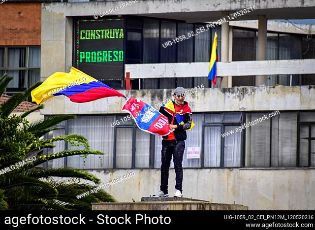 Demostrator waves the flag of Colombia at the place where the statue of Antonio Narino was located, that was removed the night before with a fence behind him...