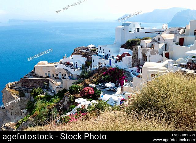 Traditional white washed Greek houses along the coastline with blue ocean in Oia, Santorini, Greece