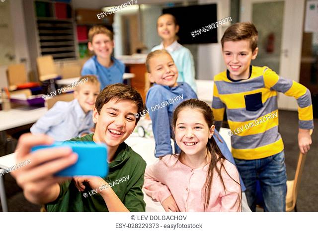 education, elementary school, children and people concept - group of kids taking selfie with smartphone in corridor