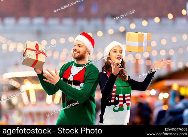 happy couple in christmas sweaters with gifts