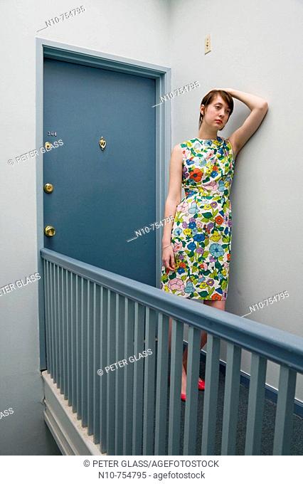Young woman posing outside her apartment door