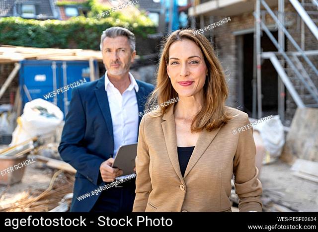 Businesswoman smiling while standing with colleague at construction site