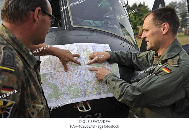 A Bundeswehr helicopter pilot (R) and a spokesperson discuss evacuation procedures of flood victims from the area around Hohengoehren