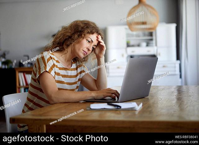 Woman getting frustrated while working on laptop at home