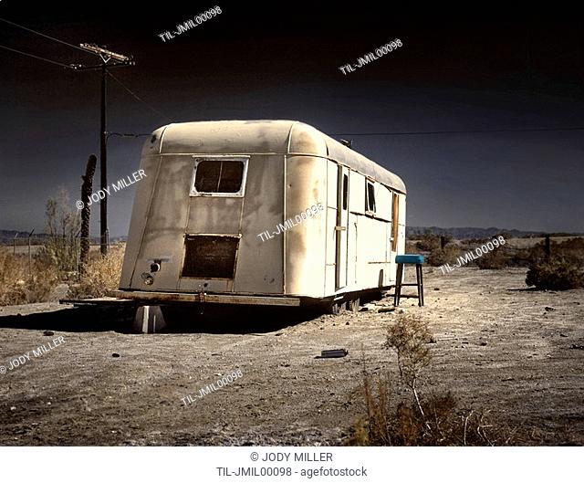 An old white caravan left to rot in the desert