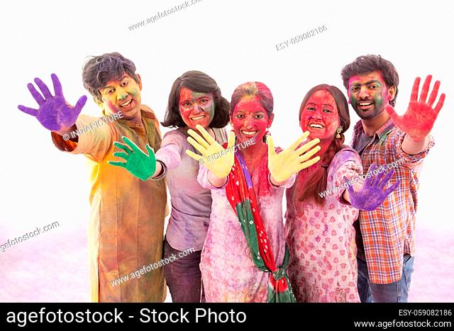 A GROUP OF FRIENDS HAPPILY SHOWING GULAL FILLED HANDS AND POSING