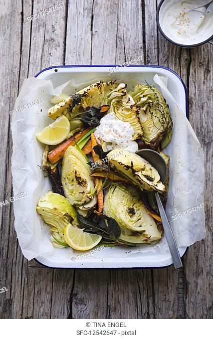 Roasted white cabbage in a baking dish with sage, carrots, lemon and a yoghurt dip
