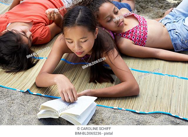 Asian girl laying and reading with friends