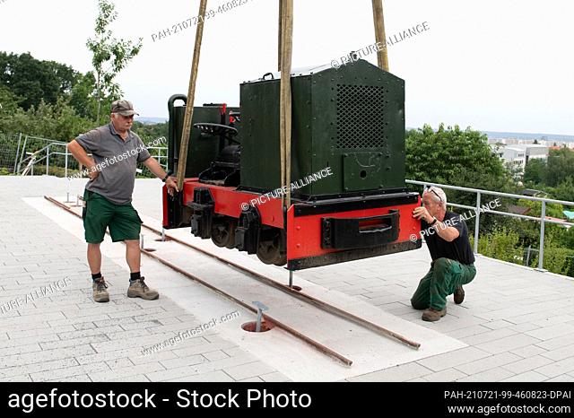 21 July 2021, Saxony, Dresden: A locomotive is placed on a track bed with a crane as a show object in the Südpark. The locomotive and three trolleys are...